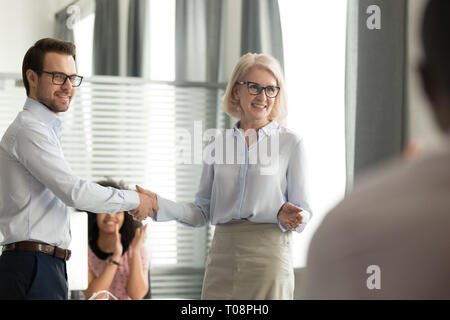 Gerne weibliche Boss zitternden Hand gratulieren männlichen Arbeitnehmer mit Förderung Stockfoto