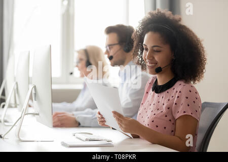 Lächelnd afrikanische Frau call center Betreiber das Headset lesen Papiere Stockfoto