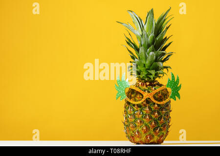 Ananas trägt Sonnenbrille auf gelbem Hintergrund Stockfoto