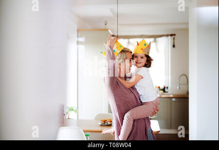 Ein Porträt von kleinen Mädchen mit Mutter Spaß zu Hause haben. Stockfoto