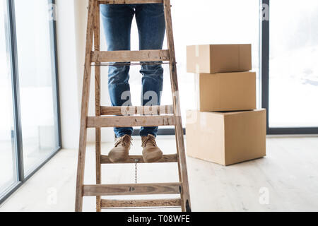 Ein Mittelteil des Menschen mit Kartons stehen auf einer Leiter, Möblierung neues Haus. Stockfoto