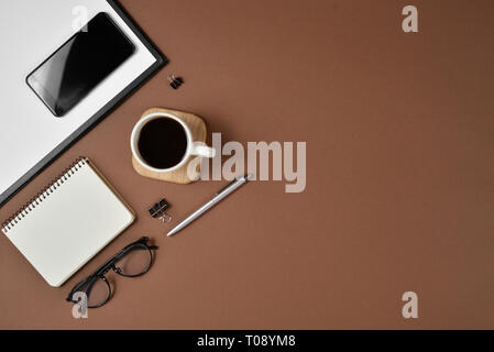Kreative Flach, Ansicht von oben Bürotisch Schreibtisch. Arbeitsbereich mit leeren Clip Board, Bürobedarf, Kugelschreiber, Notizblock, Smartphone, Gläser und Kaffee Tasse auf einem Stockfoto