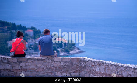 Kroatien, Hvar - Juni 2018: Paar sitzen hoch oben an der Wand, im Ocean View - Punkte auf der Strecke suchen Stockfoto