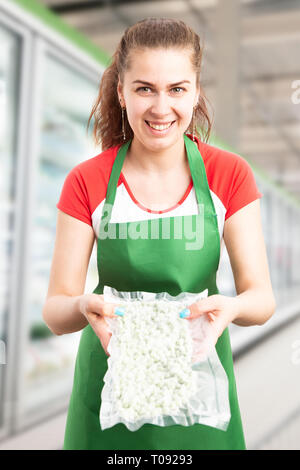 Mitarbeiterin im SB-Warenhaus oder Supermarkt Holding in der hand Tasche gefrorene grüne Bohnen als Werbung Produkte Konzept Stockfoto