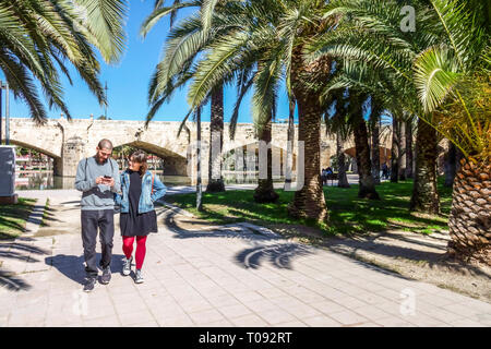 Ein Paar aus Valencia, das unter Palmen in den Valencia Turia Gardens spaziert, Spanien, in einem Garten mit Palmen spaziert Stockfoto