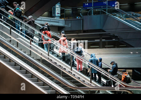 Berlin, Deutschland - März 2019: Personen mit Gepäck auf der Rolltreppe im Bahnhof (Hauptbahnhof) in Berlin. Stockfoto