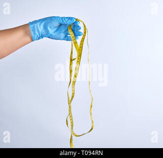 Blau sterile behandschuhte Hand mit einem gelben Maßband auf weißem Hintergrund Stockfoto