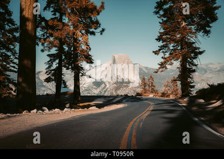 Wunderschöne Aussicht auf Wicklung Glacier Point Road mit berühmten Half Dome Gipfel im goldenen Abendlicht bei Sonnenuntergang, Yosemite National Park, Kalifornien, USA Stockfoto