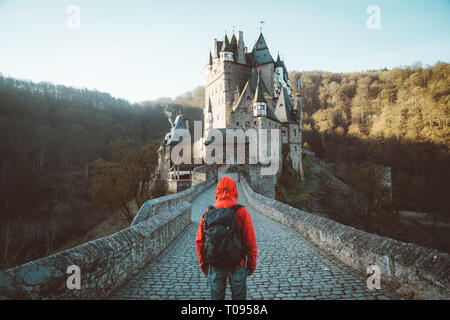 Panorama der jungen Entdecker mit Rucksack im Blick auf berühmte Burg Eltz bei Sonnenaufgang im Herbst, Rheinland-Pfalz, Deutschland Stockfoto