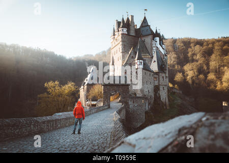 Panorama der jungen Entdecker mit Rucksack im Blick auf berühmte Burg Eltz bei Sonnenaufgang im Herbst, Rheinland-Pfalz, Deutschland Stockfoto