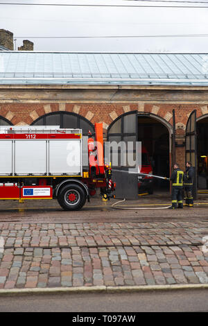 RIGA, Lettland - 16. MÄRZ 2019: Fire Truck geputzt wird - Treiber wäscht Feuerwehrmann Lkw an einer Depo-Van in einer Garage Stockfoto