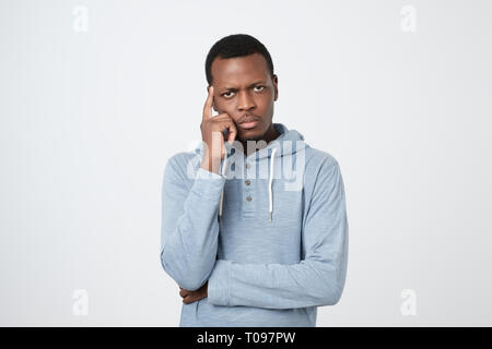 Hübscher junger afrikanischer amerikanischer Mann suchen, um sich mit durchdachten und skeptischen Ausdruck Stockfoto