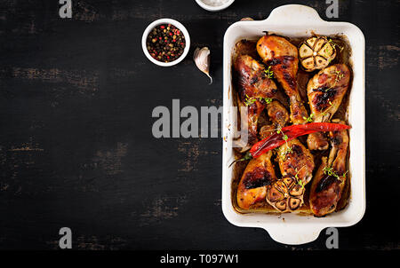 Appetitlich ofen Gebacken golden Chicken Drumsticks in einer Auflaufform auf einen dunklen Tisch. Asiatische Küche. Ansicht von oben Stockfoto