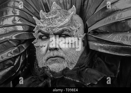 Mann mit Stacheln oder Warzen, Gesicht mit glitzert abgedeckt. Dämon mit goldenen Kragen auf schwarzem Hintergrund. Alien, Dämon, Zauberer Make-up. Fantasy Konzept Stockfoto