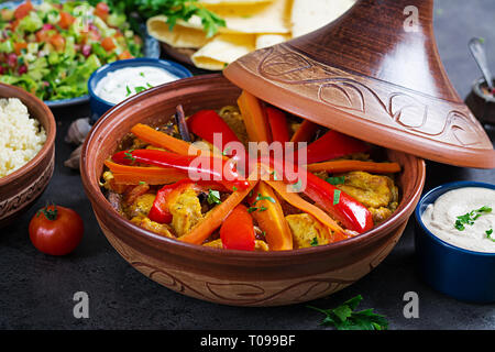 Marokkanisches Essen. Traditionelle tajine Gerichte, Couscous und frischen Salat auf rustikalen Holztisch. Tajine Hähnchen Fleisch und Gemüse. Arabische Küche. Stockfoto