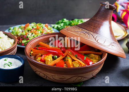 Marokkanisches Essen. Traditionelle tajine Gerichte, Couscous und frischen Salat auf rustikalen Holztisch. Tajine Hähnchen Fleisch und Gemüse. Arabische Küche. Stockfoto