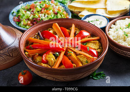 Marokkanisches Essen. Traditionelle tajine Gerichte, Couscous und frischen Salat auf rustikalen Holztisch. Tajine Hähnchen Fleisch und Gemüse. Arabische Küche. Stockfoto