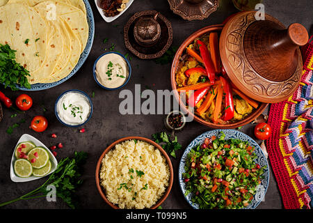 Marokkanisches Essen. Traditionelle tajine Gerichte, Couscous und frischen Salat auf rustikalen Holztisch. Tajine Hähnchen Fleisch und Gemüse. Arabische Küche. Top Stockfoto