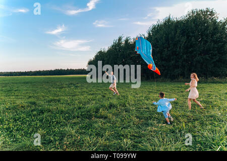 Glückliche Familie Vater, Mutter und Kind, der Sohn einen Kite auf die Natur bei Sonnenuntergang Stockfoto