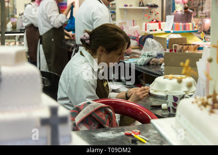 Ein Konditor, der einen Kuchen auf dem verdeckten Golden Cross Market in Oxford, Oxfordshire, Großbritannien, dekoriert Stockfoto