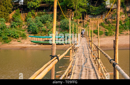 Ältere männliche Touristen gehen über wacklige Bambus Zuckerrohr Brücke über den Fluss Nam Kahn Nebenarm des Mekong, Luang Prabang, Laos, Indochina, Se Asien Stockfoto