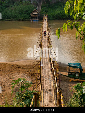 Touristen zu Fuß auf wackeligen Bambus Zuckerrohr Brücke über den Fluss Nam Kahn Nebenarm des Mekong, Luang Prabang, Laos, Indochina, Se Asien Stockfoto