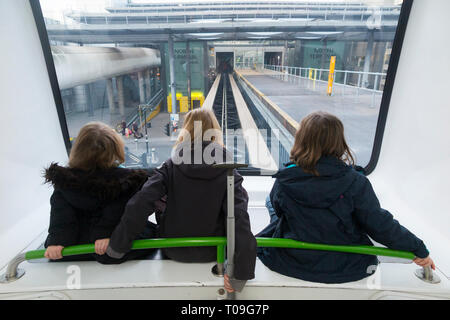 Drei Schwestern, Mädchen, Kinder, Kinder, fahren mit dem Interterminal-Shuttleservice, dem Gatwick Shuffle-Zug zwischen North Terminal und South Terminals Gatwick Airport, London, UK. (104) Stockfoto