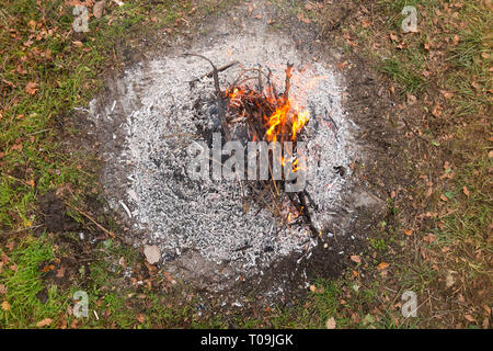 Verbrannt Lagerfeuer im Garten, Herbst, blauer Rauch über der Asche