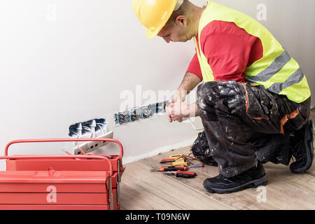 Elektriker Reparatur / Befestigung Drähte in der Wand. Stockfoto