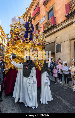 Sevilla, Spanien - 26. März: Hooded Zahlen halten eine Fließkommazahl, die Jesus Christus in der Heiligen Woche in Sevilla, Spanien am 26. März 2018 Stockfoto