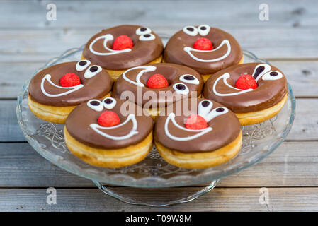 Schokolade glasierte Donuts mit lächelnden Gesichtern. geringe Schärfentiefe Stockfoto