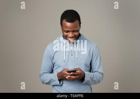 Afrikanische jungen Mann über das Handy Chatten im Internet mit Ihren Freunden. Stockfoto