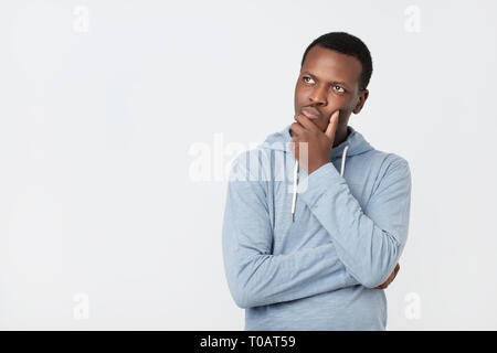 Hübscher junger afrikanischer amerikanischer Mann suchen, um sich mit durchdachten und skeptischen Ausdruck Stockfoto