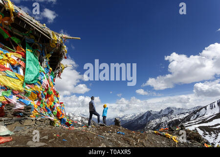 Mutter und Sohn stehen auf der Oberseite der 4,298 m Zheduo Shan, Gebetsfahnen mit wunderschönen Blick über verschneite Berge, Kangding, Sichuan, China Stockfoto