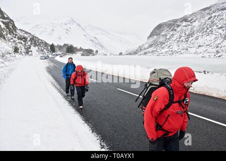 Wanderer zu Fuß durch Ogwen Valley im Schnee, Winter, Snowdonia, Gwynedd, Wales, Großbritannien Stockfoto