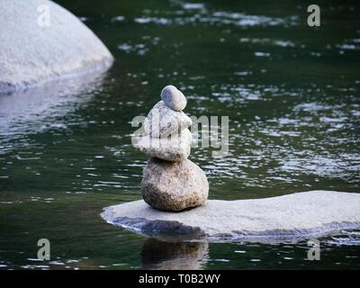 Nahaufnahme von einem Stapel von Steinen auf einem großen Felsen im Fluss Stockfoto