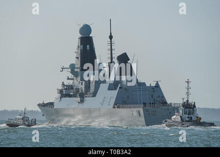 Ein Pilot Boot und Schlepper Escort der Royal Navy Typ 45 Zerstörer HMS Defender im Solent, als das Kriegsschiff fährt Portsmouth, Großbritannien am 18. März 2019. Stockfoto