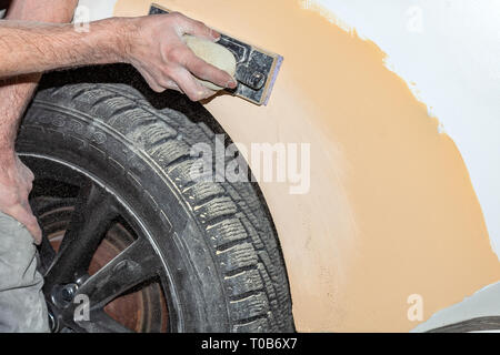 Vorbereitung für die Lackierung eines Autos mit schmirgel Absender durch einen Servicetechniker, Nivellierung, bevor Sie eine Grundierung nach der Beschädigung auf einen Teil der Stockfoto