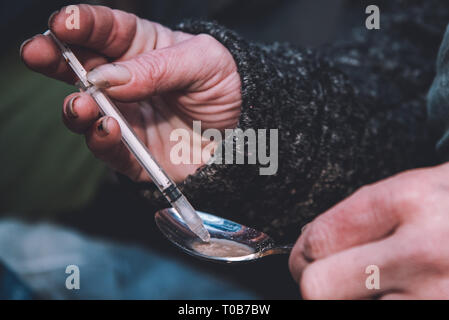 Eine weibliche Heroinsüchtiger zieht Frisch Heroin in einer Spritze zubereitet. Stockfoto