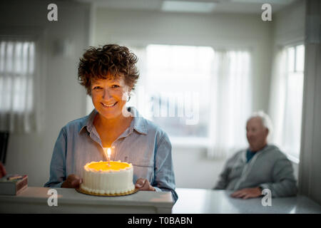 Porträt eines lächelnden reife Frau mit einem Geburtstagskuchen. Stockfoto