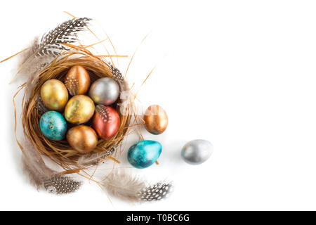 Frohe Ostern Urlaub gruss Symbol aus Naturholz gras Nest mit goldenen Wachtel Eier und Federn Studio auf weißem Hintergrund Stockfoto