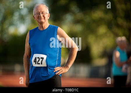 Porträt eines lächelnden älteren Mann stehend auf einem Sportplatz. Stockfoto