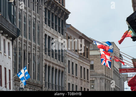 Montreal, Quebec, Kanada. Blick nach Westen, Saint Paul Street East at Saint Vincent Street an Fahnen gegen Gebäude in der Altstadt von Montreal fliegen. Stockfoto