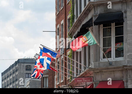 Montreal, Quebec, Kanada. Blick nach Westen auf Flaggen von einem braunen Backsteingebäude auf Saint Paul Street East at Saint Vincent Street in der Altstadt von Montreal fliegen. Stockfoto