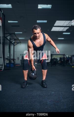 Starke Mann in Sportkleidung, übung mit kettlebell, Gewicht heben. Weightlifting Workout, Sportler in Sport oder Fitness Club, Lifter auf Training habe ich Stockfoto