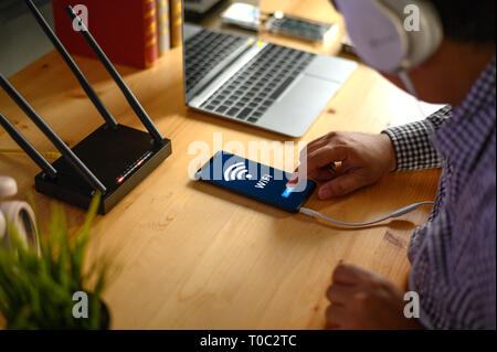 Junger Mann verbinden Router wlan auf dem Smartphone für Internet und Social Media Stockfoto
