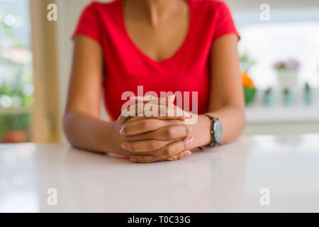 In der Nähe der jungen Frau Kreuzung Hände über weissen Tisch Stockfoto