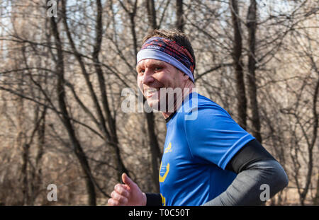 ALMATY, Kasachstan - 16. März 2019: Porträt einer stattlichen Reifen unbekannter Mann, der durch die Wälder im Frühjahr beim Marathon in der Stadt läuft Stockfoto