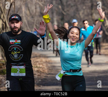 ALMATY, Kasachstan - 16. MÄRZ 2019: eine dichte Gruppe von unbekannten Männern und Frauen läuft durch ein Wäldchen im Frühjahr Marathon in der Stadt Almaty, Stockfoto