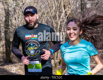 ALMATY, Kasachstan - 16. MÄRZ 2019: eine dichte Gruppe von unbekannten Männern und Frauen läuft durch ein Wäldchen im Frühjahr Marathon in der Stadt Almaty, Stockfoto